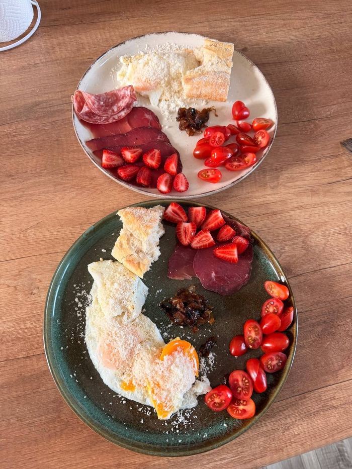 Два завтрака: вяленое мясо, клубника, томаты, яйцо с пармезаном